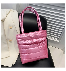 Detailed shot of pink quilted metallic puffer tote bag resting on a black leather chair