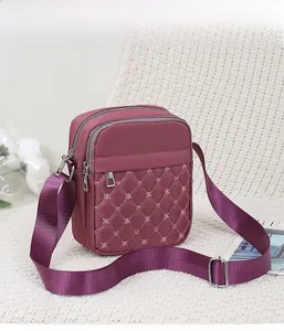 Detail view of burgundy quilted crossbody bag with star embroidery and multiple zippers