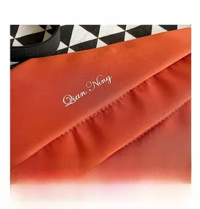 Detail of orange canvas waist bag with white stitching and decorative script logo