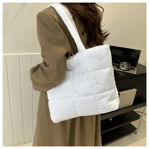 Detailed view of a white quilted tote bag with soft padded straps and large square patterns