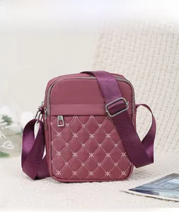 Close-up of wine red quilted oxford cloth cross-body bag with heart embroidery details