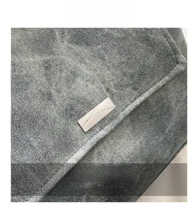 Detailed close-up showing the grey washed denim texture and rectangular logo on the bag