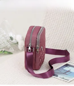 Detail of burgundy oxford cloth bag with quilted diamond pattern and zipper pockets