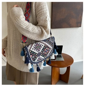 Close-up of bohemian woven crossbody bag with colorful tassels and patterned shoulder strap