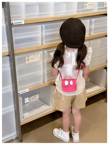 Vue arrière d'une fille portant un mini sac bandoulière rose avec un nœud blanc 3D