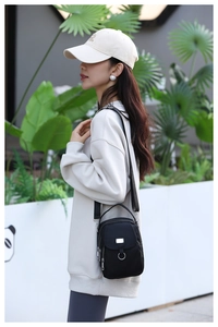 Detail view of a compact black nylon crossbody phone bag with adjustable wide strap