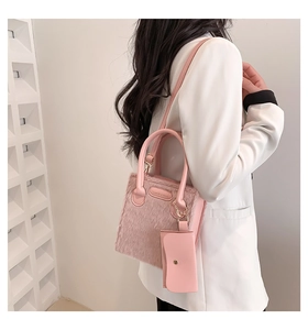 Detailed close-up of pink faux fur crossbody bag featuring leather straps and logo pouch