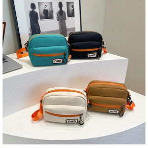 Four colorful canvas crossbody bags in blue black white and brown with bright orange straps