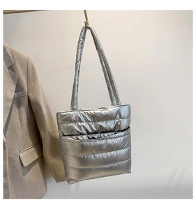Close-up of a silver quilted puffer tote bag with metallic finish and wide shoulder straps