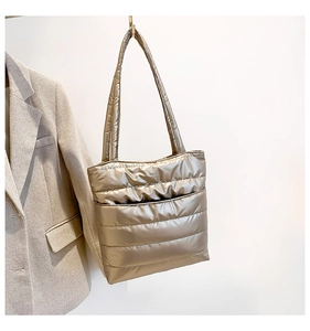 Detail view of champagne gold quilted tote bag with padded texture and slim straps