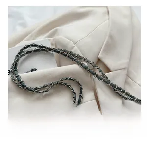 Detail of silver metal chain interwoven with blue denim fabric on a beige blazer