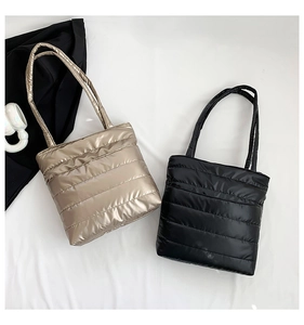 Detail of quilted down tote bags in champagne gold and black with padded straps