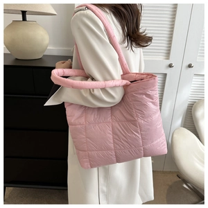 Detail of light pink quilted tote bag with thick handles and textured stitching