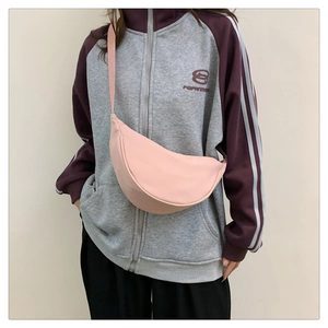 Borsa a tracolla rosa a mezzaluna indossata da una modella con una felpa grigia chiara