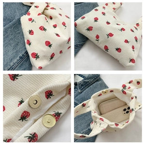 Detail view of corduroy tote bag with strawberry print and magnetic metal closure