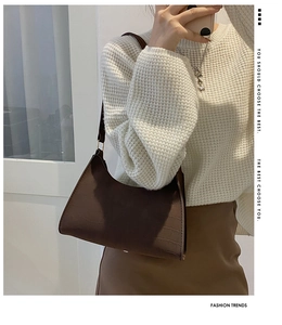 Close-up of retro dark brown crocodile pattern underarm bag with a minimalist trapezoid shape