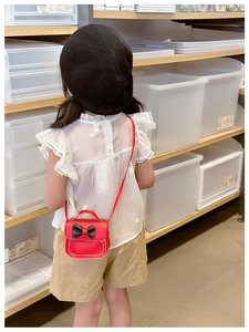 Détail du mini sac en cuir rouge pour enfant avec nœud noir et bandoulière porté