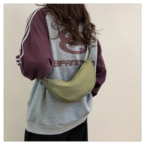 Dettaglio della borsa a tracolla a mezzaluna in nylon verde avocado indossata da una modella