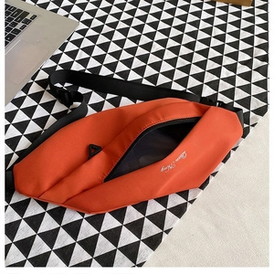 Detailed close-up of orange nylon chest bag with zipper and adjustable strap