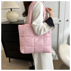 Detailed view of pink quilted puffer tote bag on shoulder for size and texture display