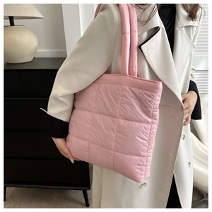 Close-up of pink quilted puffer tote bag shown on model with soft padded fabric texture