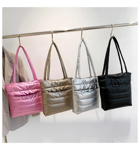 Quilted puffer tote bags in metallic pink, bronze, silver and black displayed on a rack