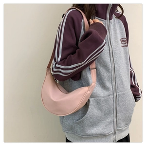 Vista laterale di una borsa a tracolla rosa in nylon indossata con felpa casual grigia