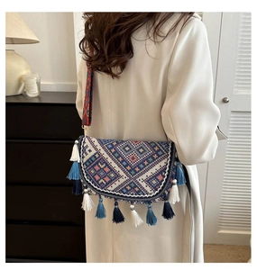 Detail of bohemian woven crossbody bag with geometric patterns and long fringes on side