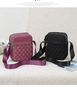 Detail of burgundy and black quilted oxford crossbody bags with three zipper pockets