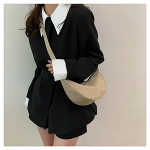 Borsa a tracolla minimalista a mezza luna beige indossata da una modella per un look di classe