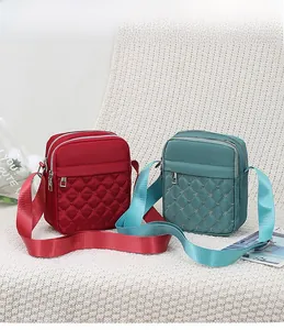 Detail of red and teal nylon crossbody bags with diamond quilting and triple zippers