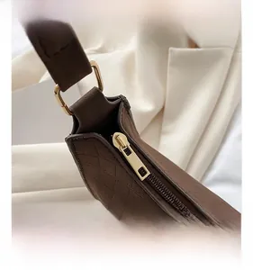 Close-up of golden zipper and hardware on vintage brown crocodile pattern baguette bag