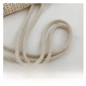 Close-up detail of the woven texture and dual braided handles on the beige straw tote bag