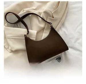 Detailed close-up of dark brown faux crocodile texture handbag on white blazer