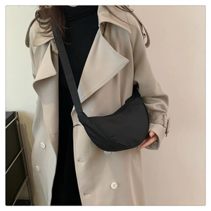 Dettaglio di una borsa a tracolla nera a mezzaluna in nylon indossata da una modella