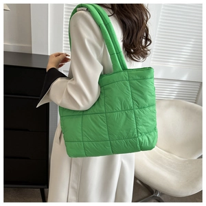 Close-up of a vibrant green quilted puffer tote bag on a shoulder for daily use