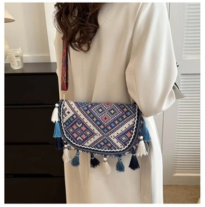 Detail of bohemian knitted bag with geometric patterns, colorful tassels and wide strap