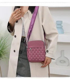 Detail of burgundy quilted nylon crossbody bag with adjustable wide shoulder strap on model