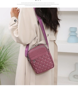 Close-up of a purple quilted crossbody bag with star stitching and adjustable strap