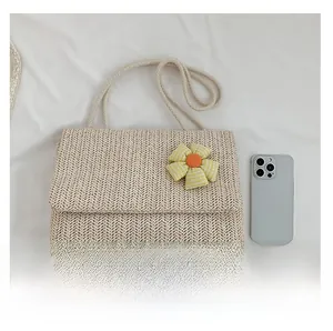 Detail of cream straw woven tote bag with a checkered flower charm and rope straps