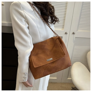 Detail view of brown faux suede shoulder bag with chain strap and metal buckle