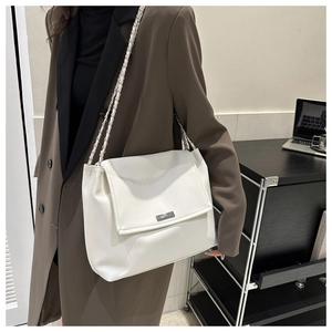 Detailed view of white PU leather shoulder bag with silver metal chain strap and flap closure