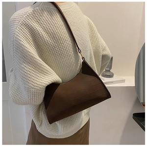 Detailed view of brown crocodile embossed hobo bag worn by model in a minimalist setting