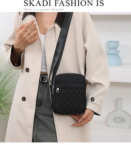 Close-up of a black quilted nylon crossbody bag with diamond stitching on a model