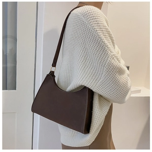 Detailed view of deep brown matte baguette bag with gold metal buckle on a shoulder strap