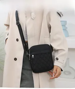Detailed view of black quilted crossbody bag with adjustable strap and metal zipper on model