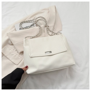 Detail of white leather shoulder bag featuring silver chain strap and metallic buckle decoration