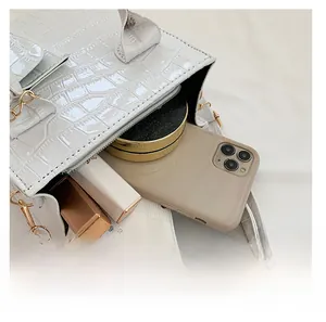 Innenkapazität der weißen Handtasche mit Krokostruktur zeigt Handy und Kosmetik