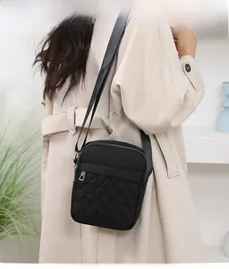 Detail of black quilted oxford cross-body bag featuring silver zippers and adjustable strap