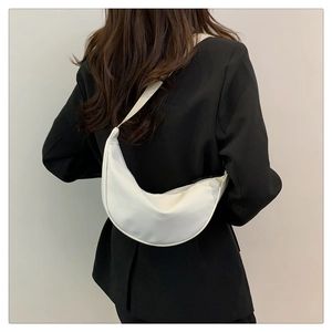 Borsa a tracolla bianca minimalista a mezzaluna per donna indossata da una modella